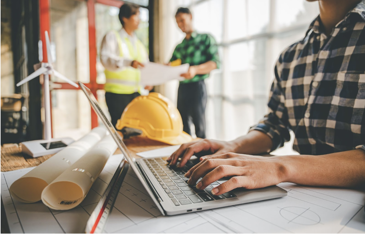 person working on a laptop with a hard hat
